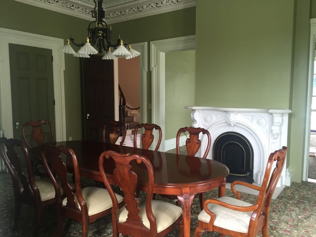 Dining room table in dining room with antique fireplace and green walls 