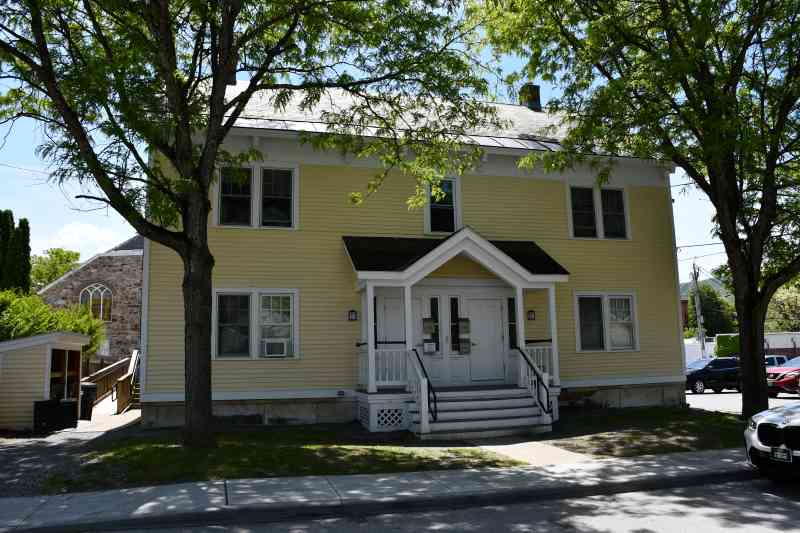 Lovely yellow house shaded by large trees as seen from Pleasant street