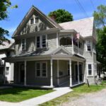 Green Victorian house with shade tree in front yard