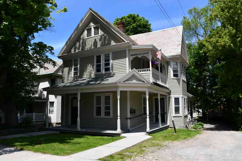 Green Victorian house with shade tree in front yard