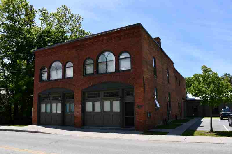Antique brick firehouse converted to apartments, still looks like it has two garage doors.