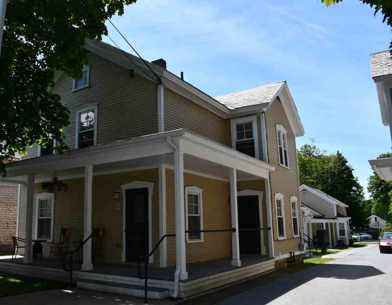 Apartment complex featuring gold colored buildings with driveway going between units.