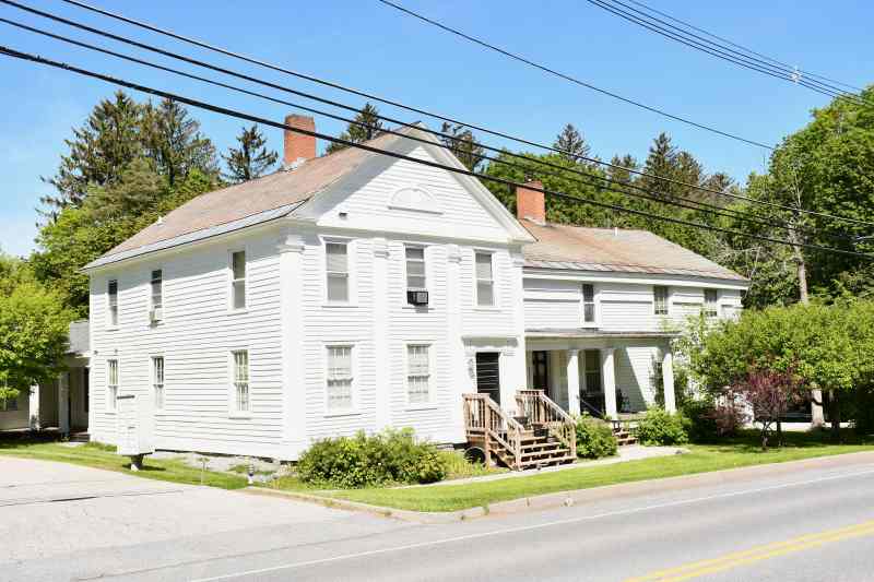 Historic large white house with porch.