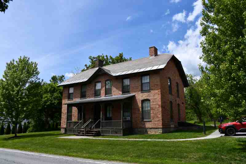 Historic brick building and green lawn viewed from road