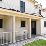 Exterior view of yellow apartment building with front porch