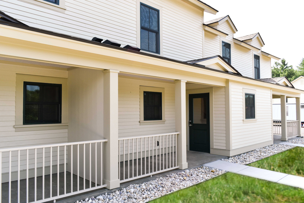 Exterior view of yellow apartment building with front porch